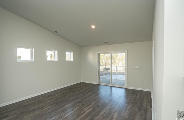 spare room featuring dark wood-type flooring and vaulted ceiling