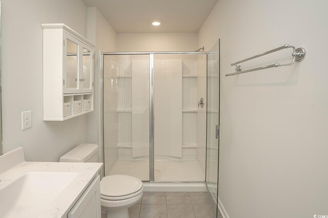 bathroom with toilet, vanity, an enclosed shower, and tile patterned flooring