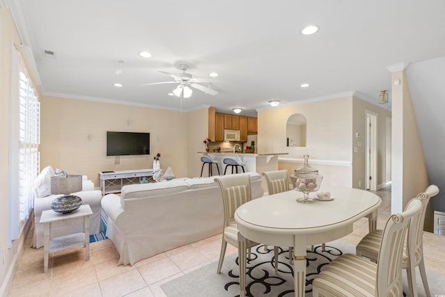 dining space featuring ceiling fan, crown molding, and light tile patterned floors