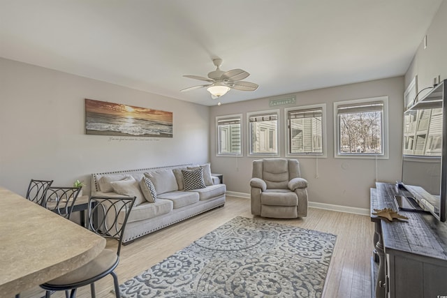living room with plenty of natural light, a ceiling fan, light wood-style floors, and baseboards