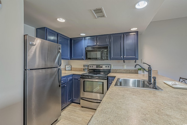 kitchen with appliances with stainless steel finishes, a sink, light countertops, recessed lighting, and blue cabinets