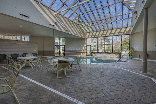 indoor pool featuring an indoor hot tub, outdoor dining area, a patio area, and a lanai