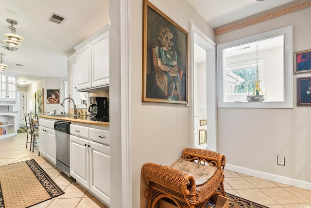 kitchen with light tile patterned floors, dishwasher, hanging light fixtures, white cabinets, and sink