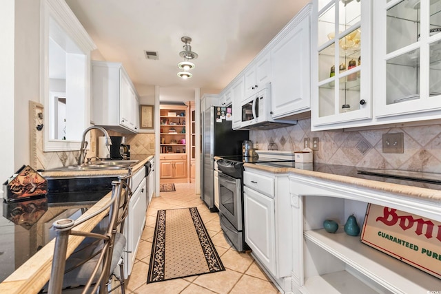 kitchen featuring stainless steel electric stove, white cabinets, decorative backsplash, sink, and light tile patterned floors