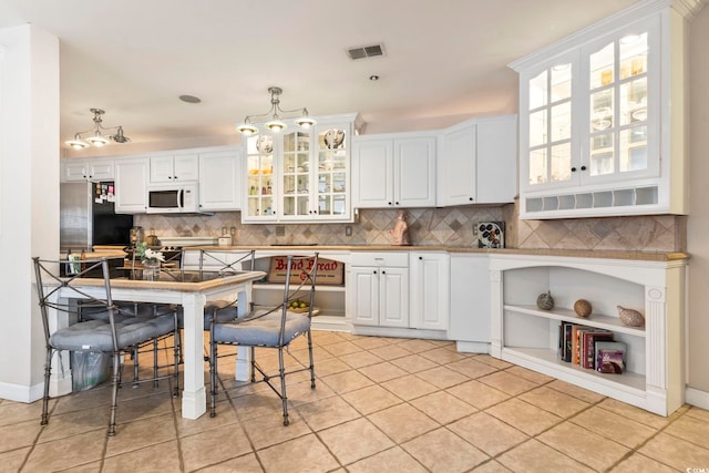 kitchen featuring decorative light fixtures, white cabinetry, stainless steel appliances, and light tile patterned flooring