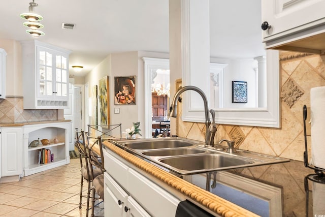 kitchen with backsplash, a kitchen bar, sink, light tile patterned floors, and white cabinets