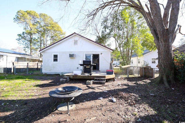 rear view of house with a fire pit, a deck, a yard, and an AC wall unit