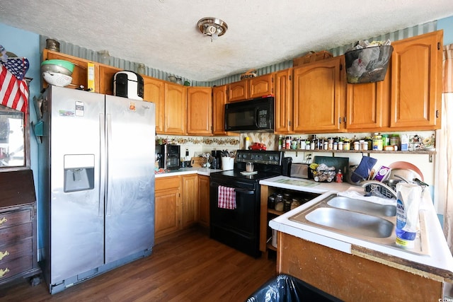 kitchen featuring dark wood-type flooring, a textured ceiling, black appliances, and sink