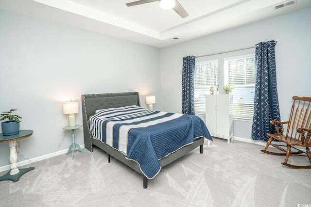 carpeted bedroom featuring ceiling fan and a raised ceiling