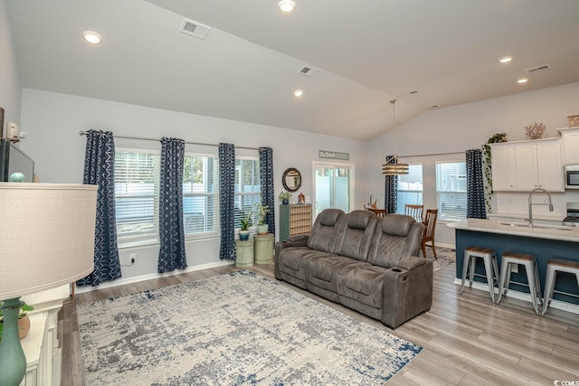 living room with lofted ceiling, light hardwood / wood-style floors, and sink