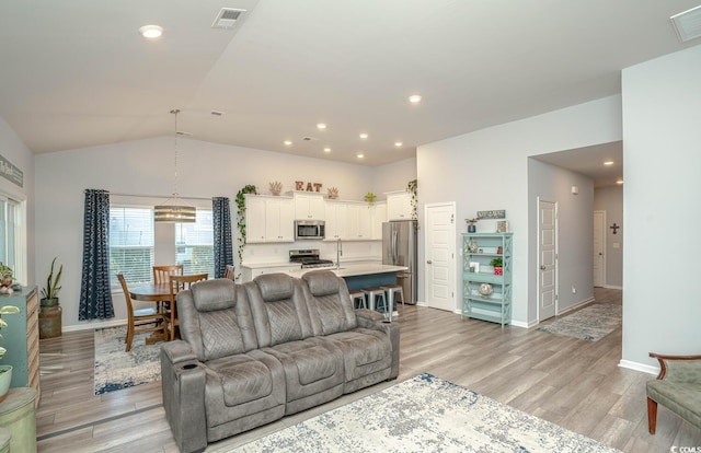 living room featuring vaulted ceiling and light hardwood / wood-style floors