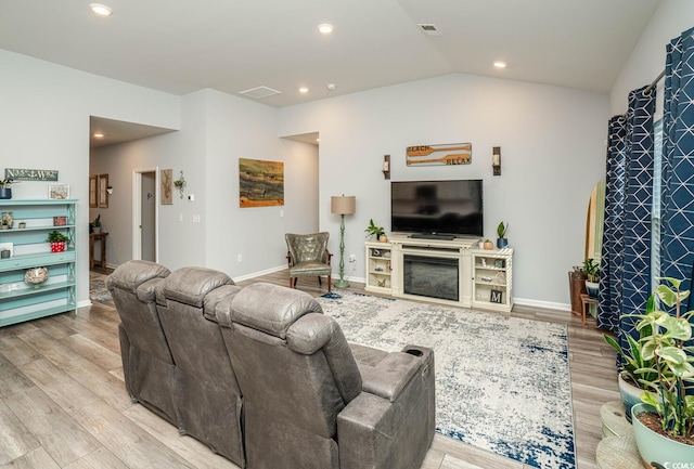 living room with vaulted ceiling, a fireplace, and light hardwood / wood-style flooring