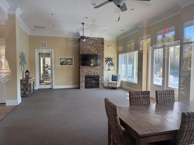 interior space with ceiling fan, ornamental molding, a stone fireplace, and wooden ceiling