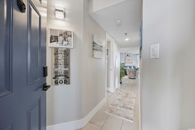 corridor featuring light tile patterned flooring and a textured ceiling