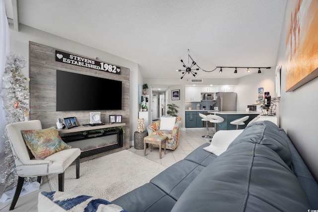 living room with an inviting chandelier, a fireplace, a textured ceiling, and track lighting