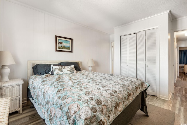 bedroom featuring a textured ceiling, a closet, ornamental molding, and wood-type flooring