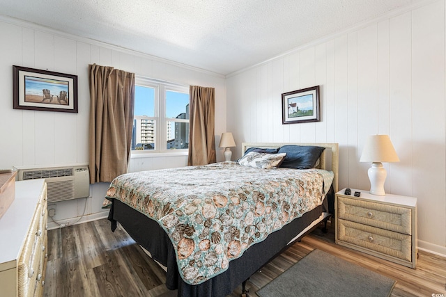 bedroom with an AC wall unit, dark hardwood / wood-style floors, a textured ceiling, and ornamental molding