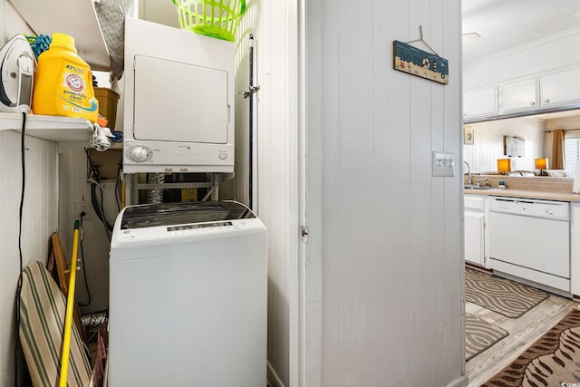 laundry room featuring stacked washer / dryer, sink, and wood walls