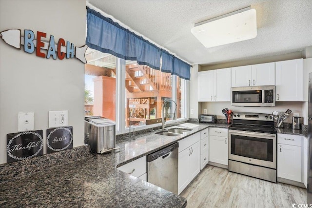 kitchen with stainless steel appliances, a textured ceiling, white cabinetry, and sink