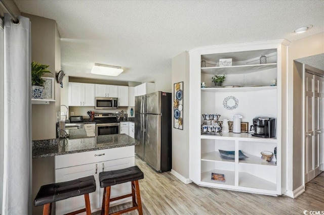 kitchen featuring appliances with stainless steel finishes, light wood-type flooring, a textured ceiling, white cabinets, and sink