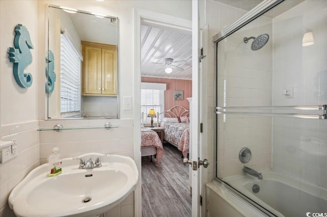 bathroom with bath / shower combo with glass door, ceiling fan, hardwood / wood-style flooring, and sink