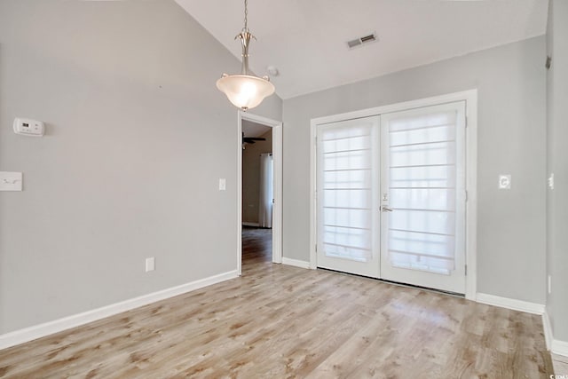 interior space featuring vaulted ceiling, french doors, and light wood-type flooring