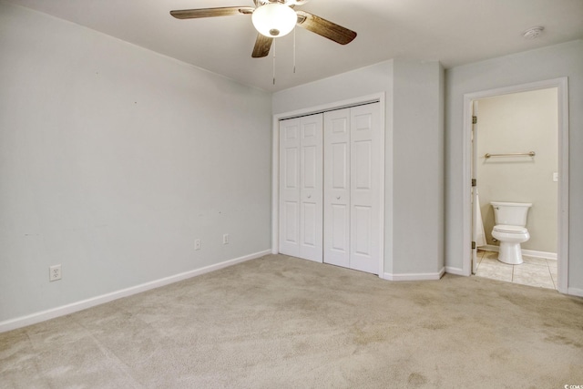 unfurnished bedroom with light carpet, ceiling fan, a closet, and ensuite bath