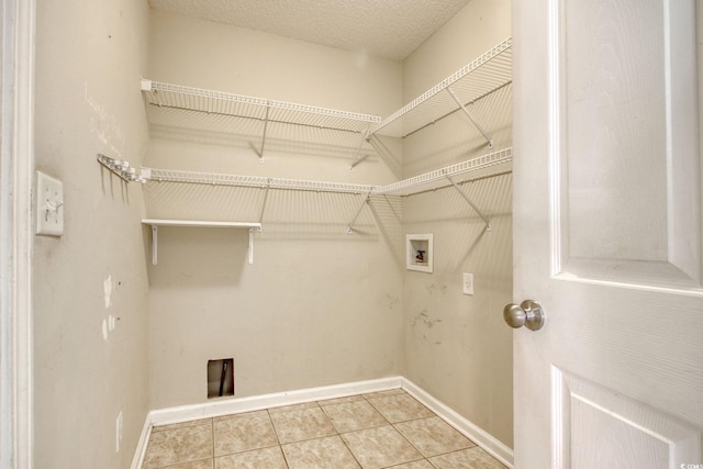 laundry area featuring light tile patterned floors, hookup for a washing machine, and a textured ceiling