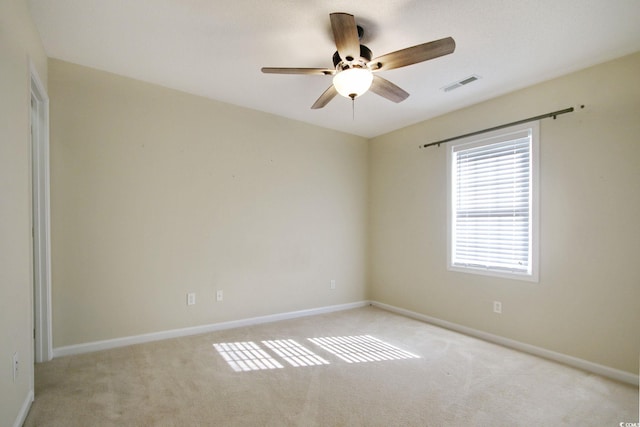 spare room with ceiling fan and light carpet