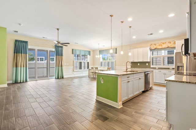 kitchen featuring white cabinetry, stainless steel dishwasher, sink, pendant lighting, and a center island with sink