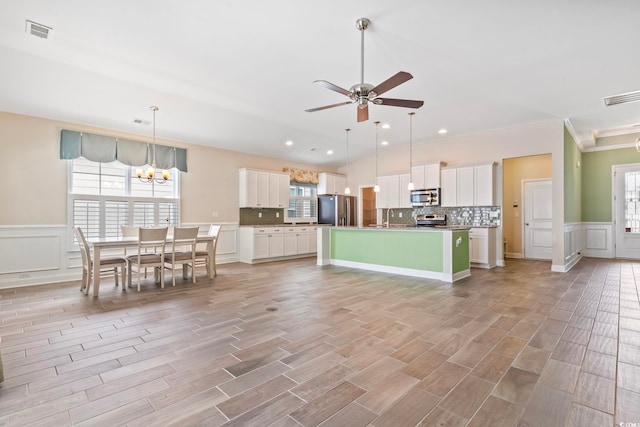 kitchen with white cabinets, stainless steel appliances, plenty of natural light, and an island with sink