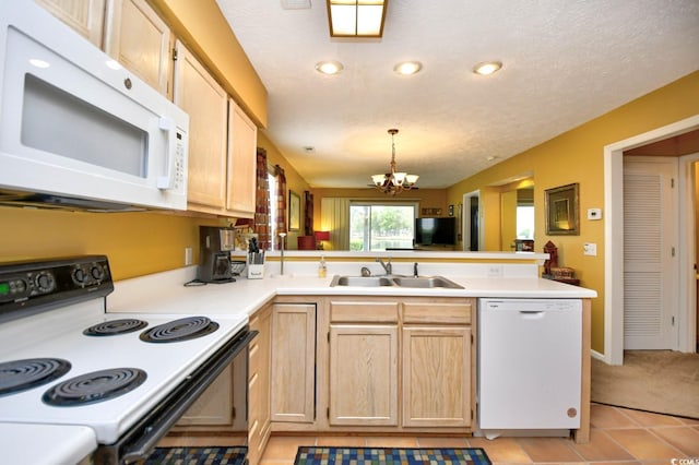 kitchen featuring white appliances, a peninsula, light countertops, light brown cabinetry, and a sink