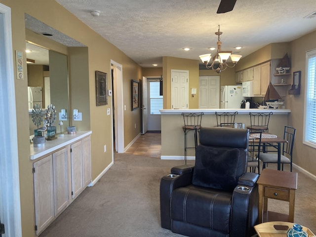 carpeted living area with a wealth of natural light, baseboards, a chandelier, and a textured ceiling