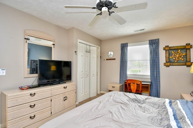 bedroom with a ceiling fan, baseboards, visible vents, and a textured ceiling