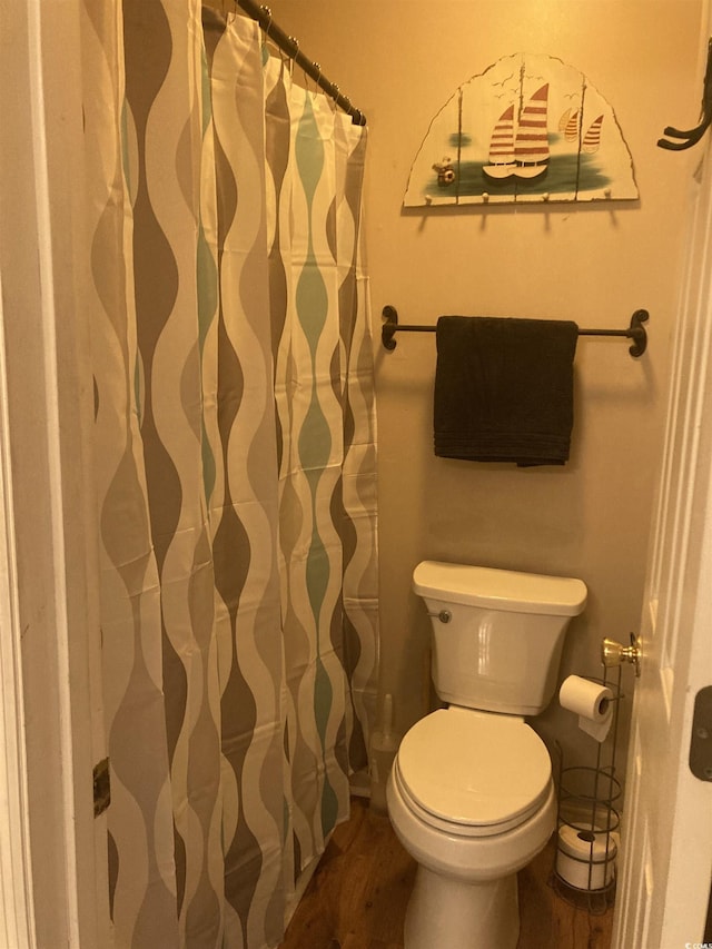 full bathroom with toilet, a shower with curtain, and wood finished floors