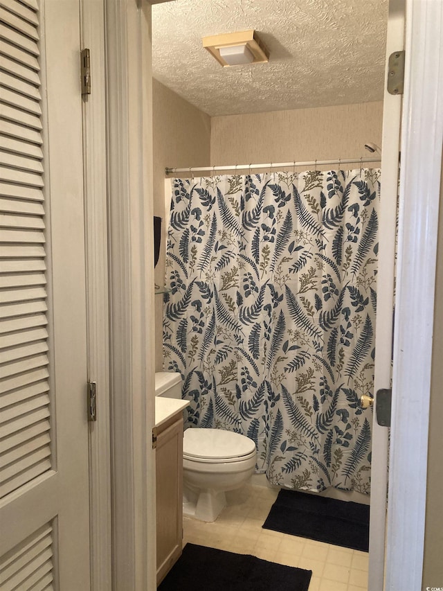 bathroom featuring a textured ceiling, curtained shower, toilet, vanity, and tile patterned floors