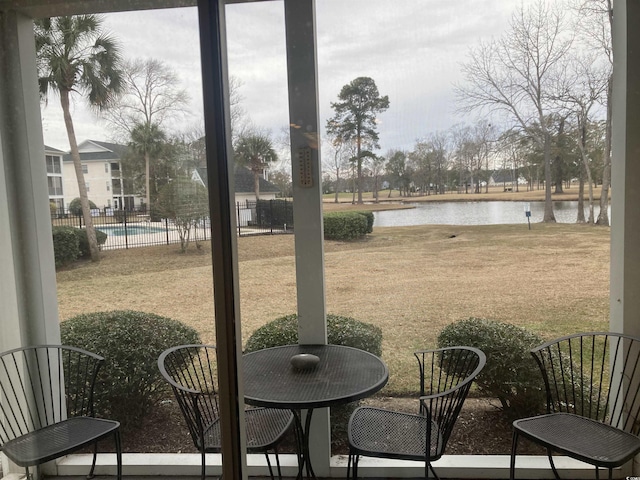 exterior space with outdoor dining area, a water view, fence, and a community pool