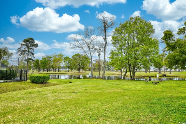 view of home's community featuring a yard, a water view, and fence