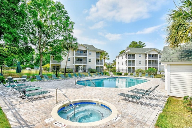 community pool featuring a hot tub, fence, and a patio