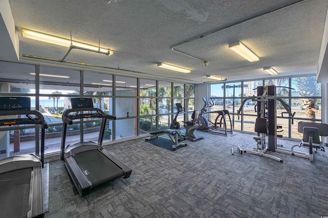 gym with a wall of windows, a textured ceiling, and dark colored carpet