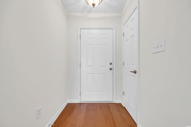 doorway featuring a textured ceiling and light hardwood / wood-style flooring