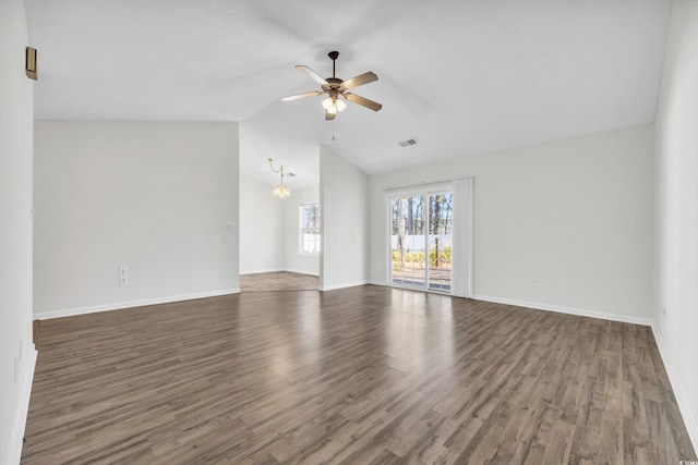 spare room featuring ceiling fan with notable chandelier, dark wood-type flooring, and lofted ceiling