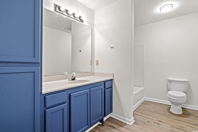 full bathroom featuring toilet, vanity, hardwood / wood-style flooring, tub / shower combination, and a textured ceiling