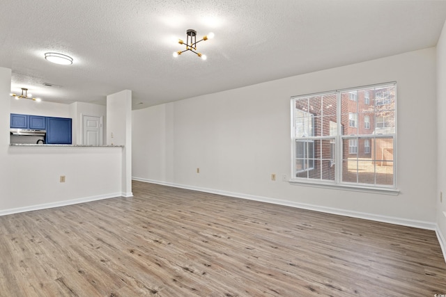 unfurnished living room featuring a textured ceiling, light hardwood / wood-style floors, and a notable chandelier