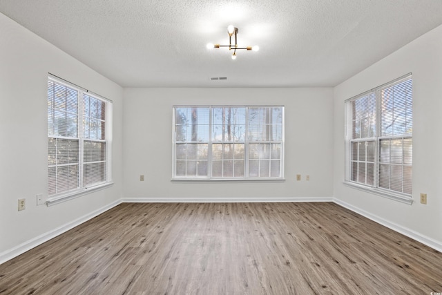 unfurnished room featuring light wood-type flooring and a textured ceiling