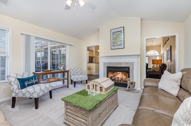 living room with ceiling fan, a tile fireplace, light carpet, and vaulted ceiling