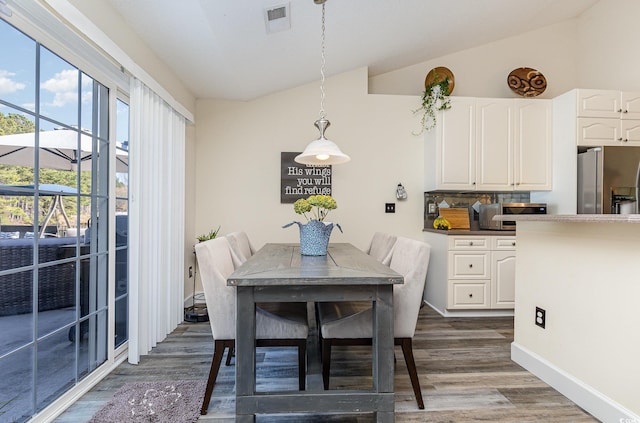 dining room with vaulted ceiling, dark hardwood / wood-style flooring, and plenty of natural light