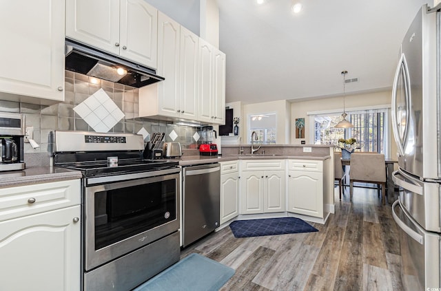 kitchen with backsplash, kitchen peninsula, appliances with stainless steel finishes, and white cabinetry