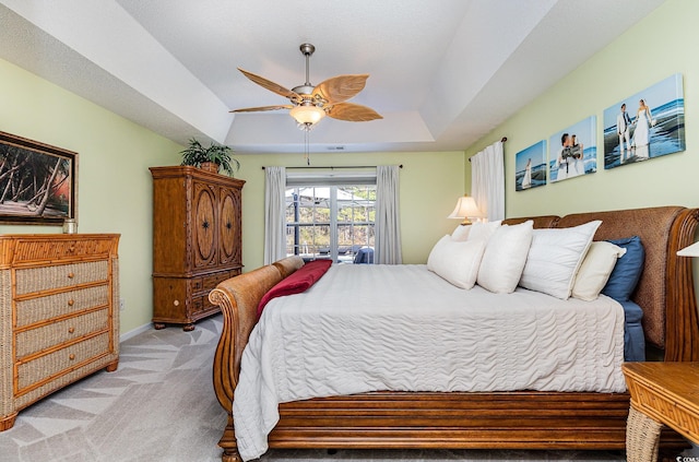 carpeted bedroom featuring a raised ceiling and ceiling fan