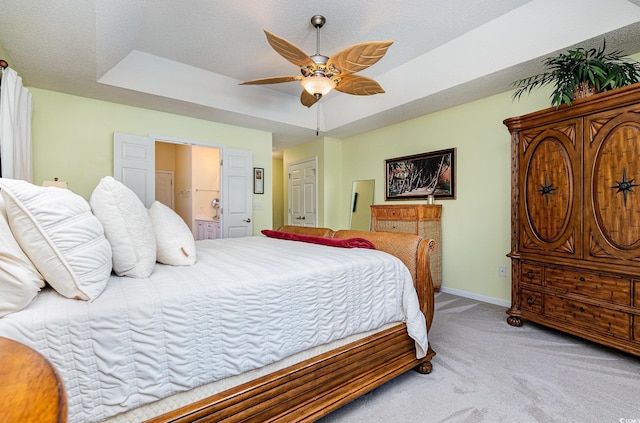 bedroom with a raised ceiling, ensuite bath, ceiling fan, and carpet flooring